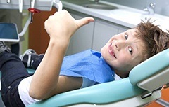 Smiling child in dental chair giving thumbs up