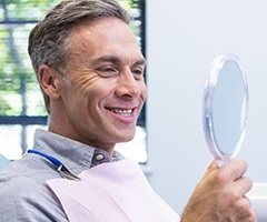 man smiling into dental mirror