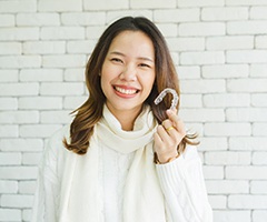 Woman holding Invisalign clear aligner. 
