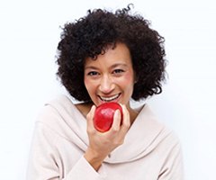 smiling woman biting into a red apple