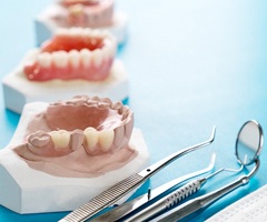 dentures sitting next to dental tools