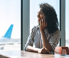 person smiling and talking on the phone in an airport