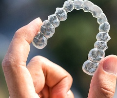 A person holding a clear aligner.