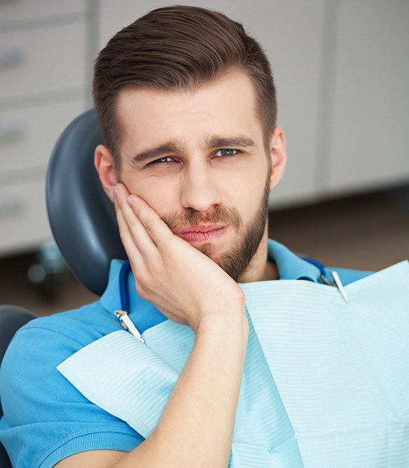 Man in dental chair holding jaw