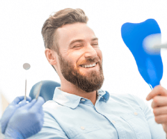 Man in dental chair looking at smile