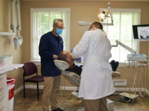 Two dentists helping a patient.
