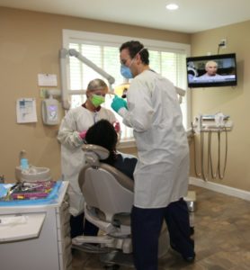 Two dentists helping a patient.