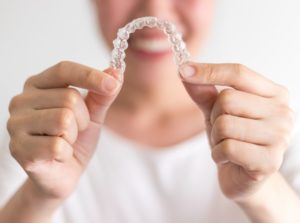 Smiling woman holds Invisalign in Charlottesville in front of her