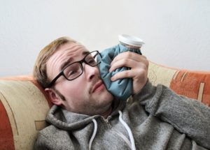 man holding cold compress to his face after dental implant surgery in Charlottesville